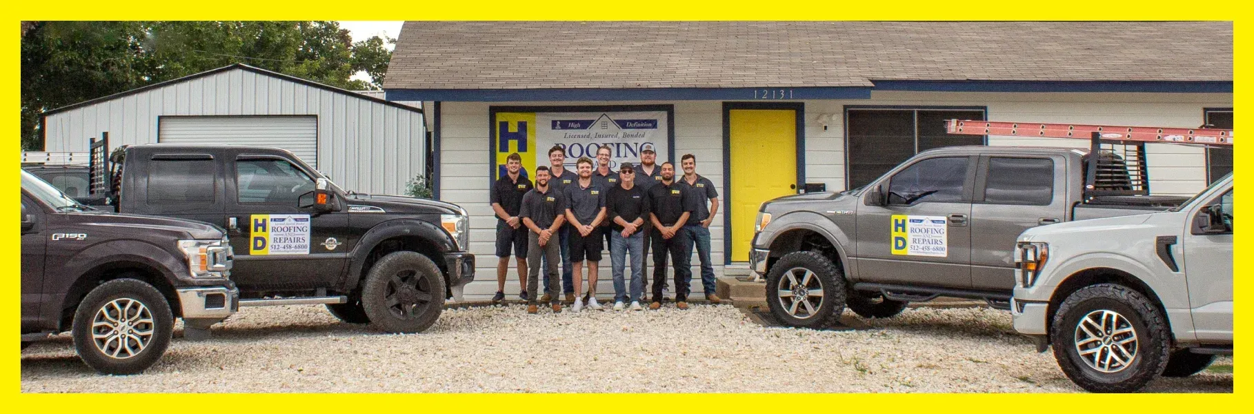 Group of men in black shirts stand in front of a building with trucks parked around them.