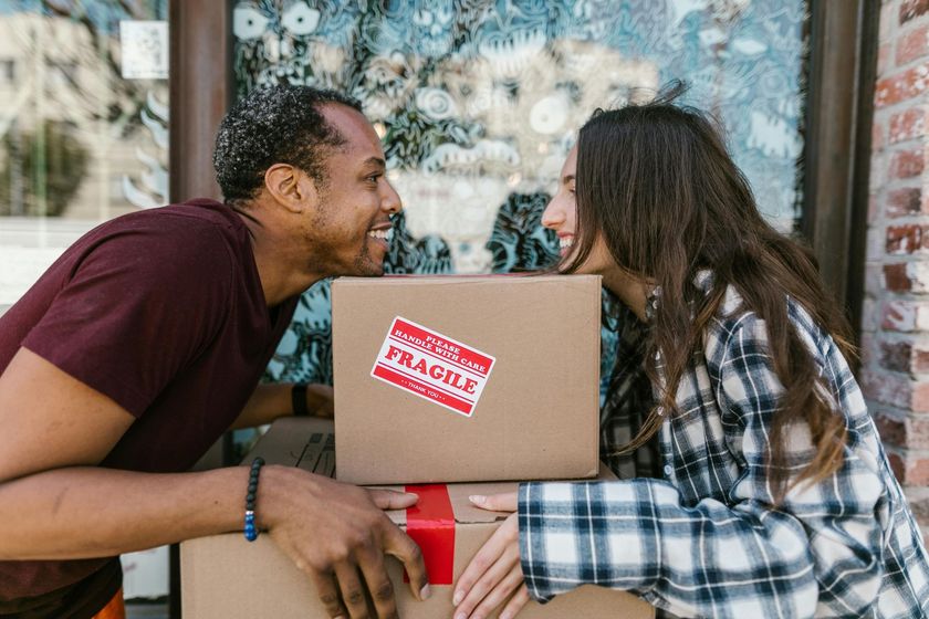 A man and a woman are looking at each other while holding boxes.