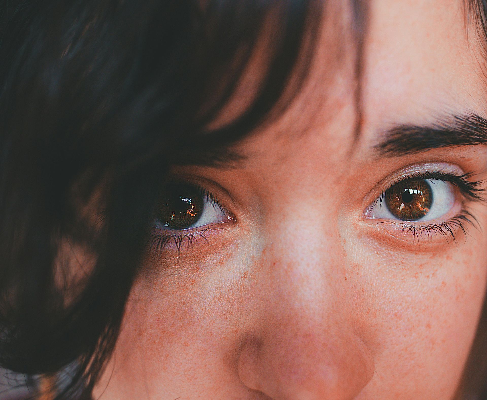 Close-up of woman's face, brown eyes, dark hair, and light skin.