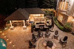 Nighttime outdoor patio with a bar, seating areas, fire pit, and pool.
