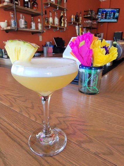 A cocktail in a martini glass with a pineapple slice on top