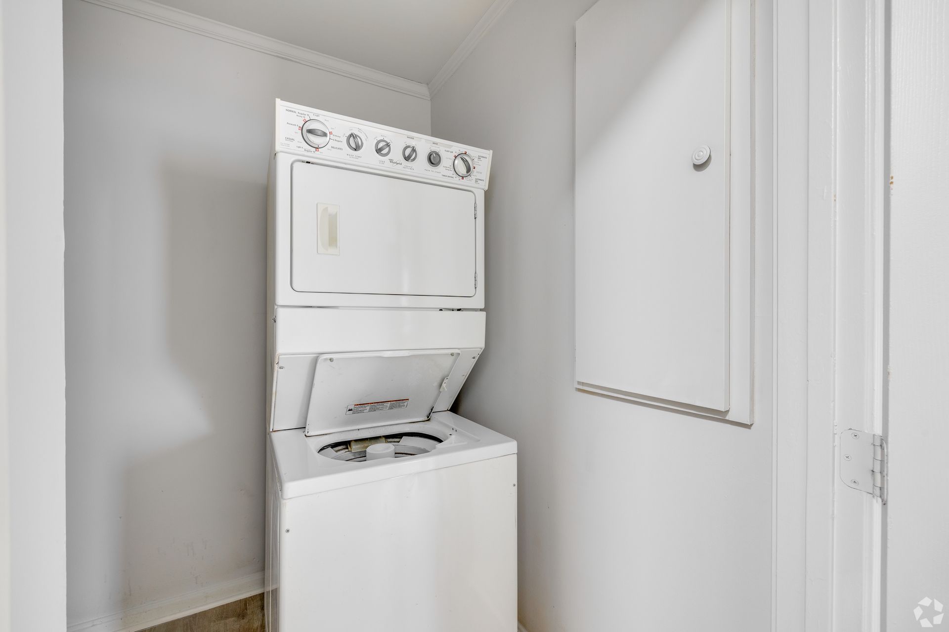 Stacked white washer and dryer in a small laundry room.