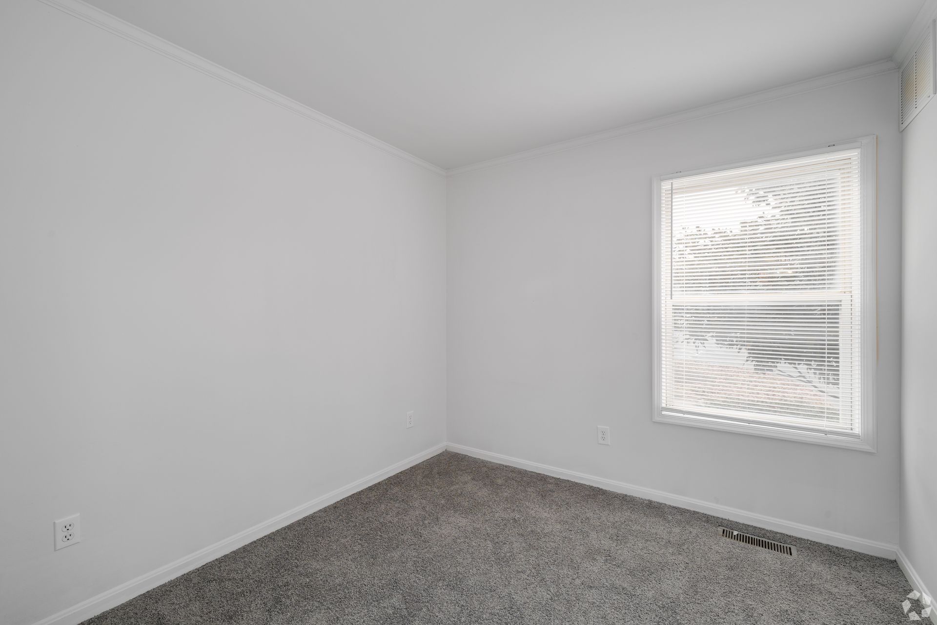 Empty room with gray carpet, white walls, and a window.