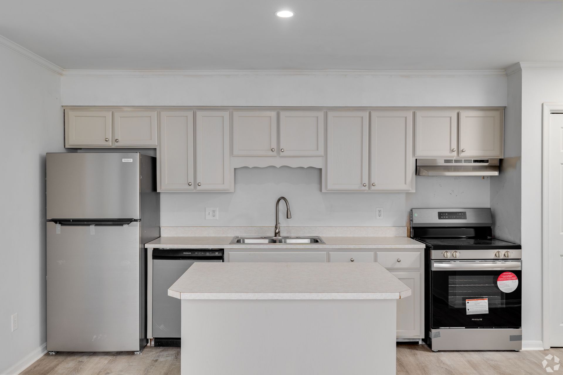 Kitchen with light-colored cabinets, stainless steel appliances, a center island, and a light countertop.