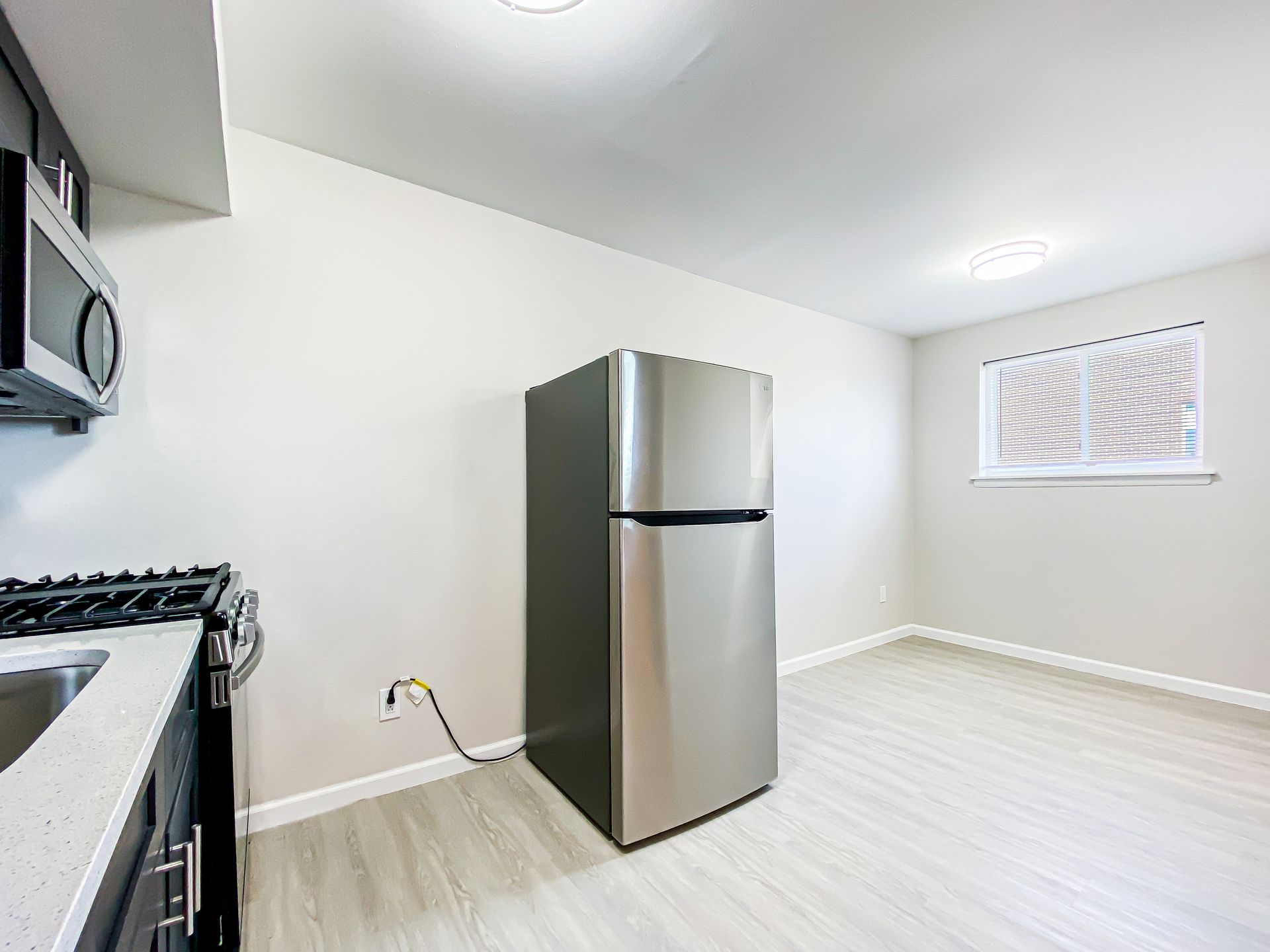 Kitchen with stainless steel refrigerator, stove, and microwave against a light grey wall.