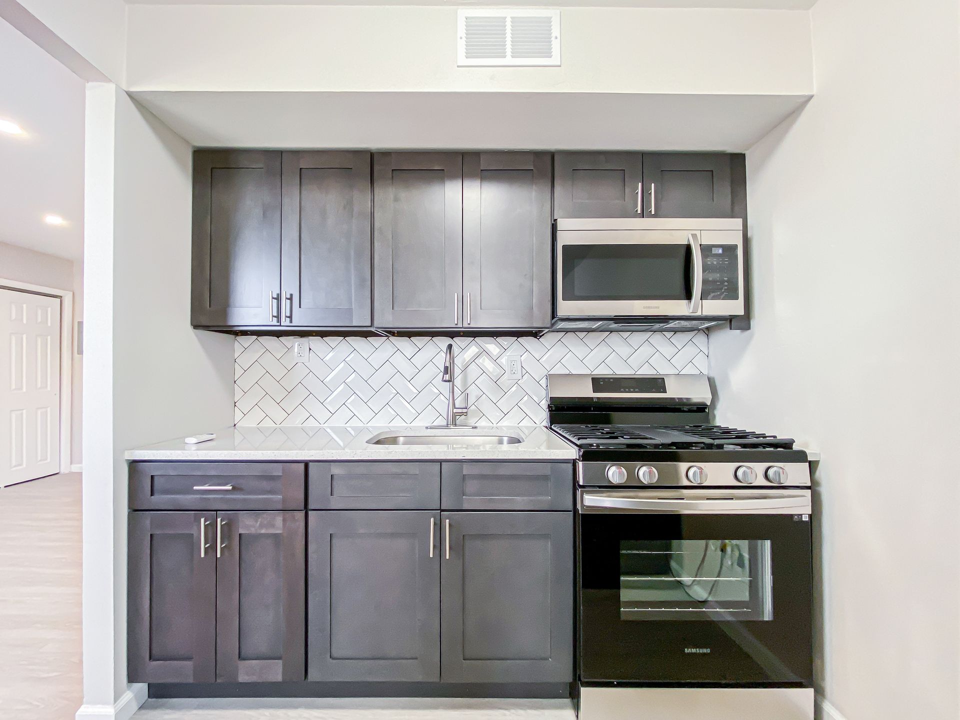 Gray kitchen with cabinets, stainless steel appliances, and a tiled backsplash.