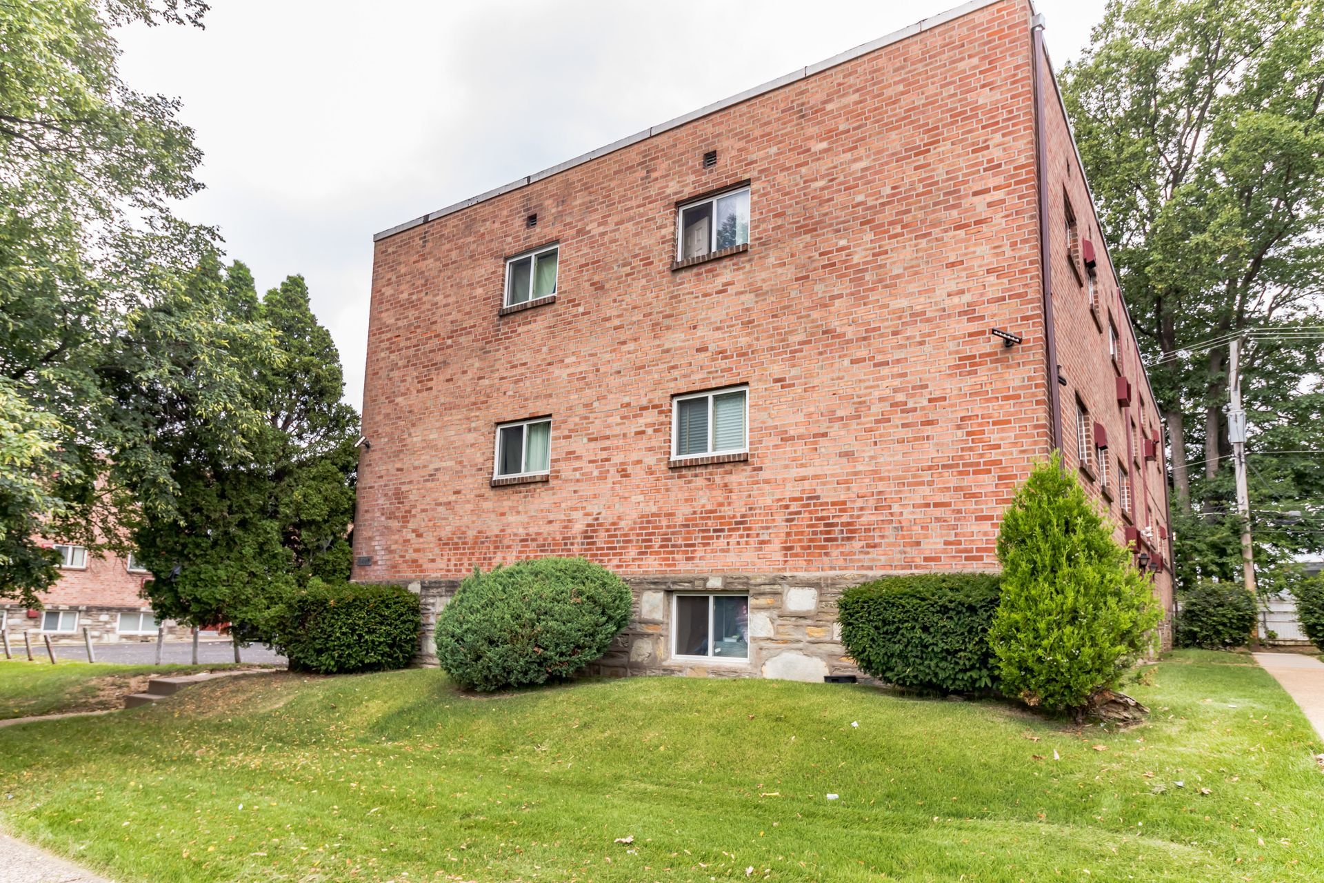 Brick apartment building with windows and green lawn.
