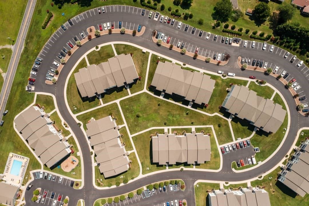Aerial view of an apartment complex with multiple buildings, a circular road, and parking lots.