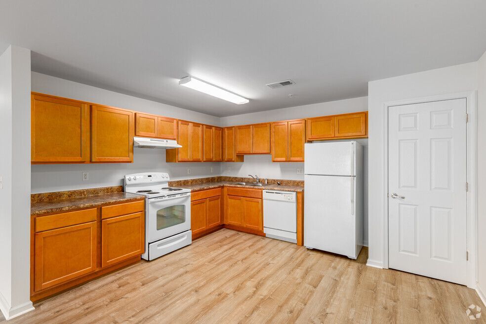 Kitchen with light wood cabinets, white appliances, and wood-look flooring.