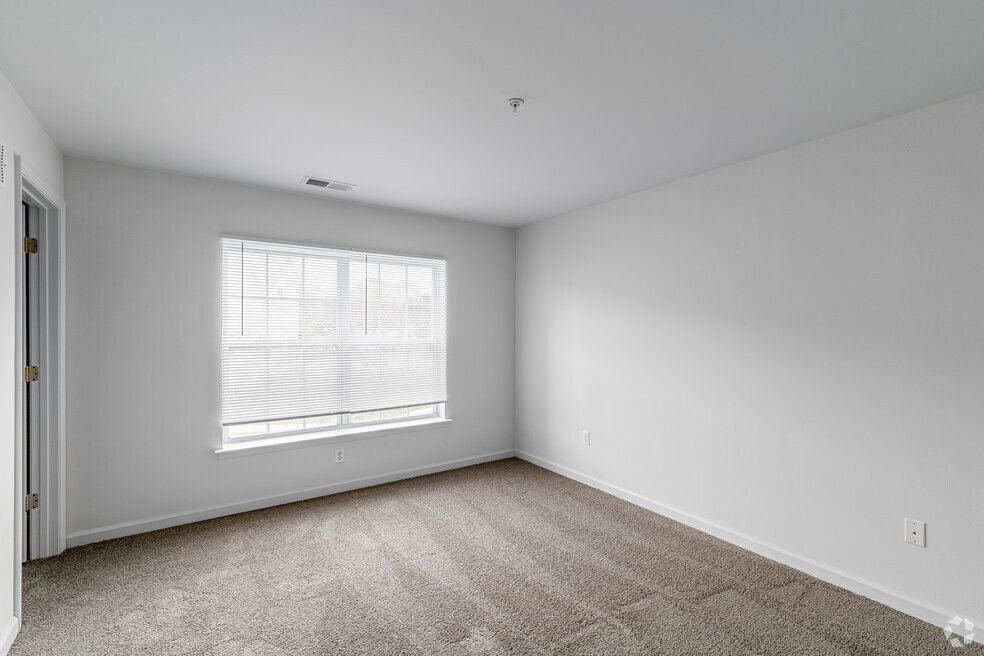 Empty room with light gray carpet, white walls, and a window with blinds.