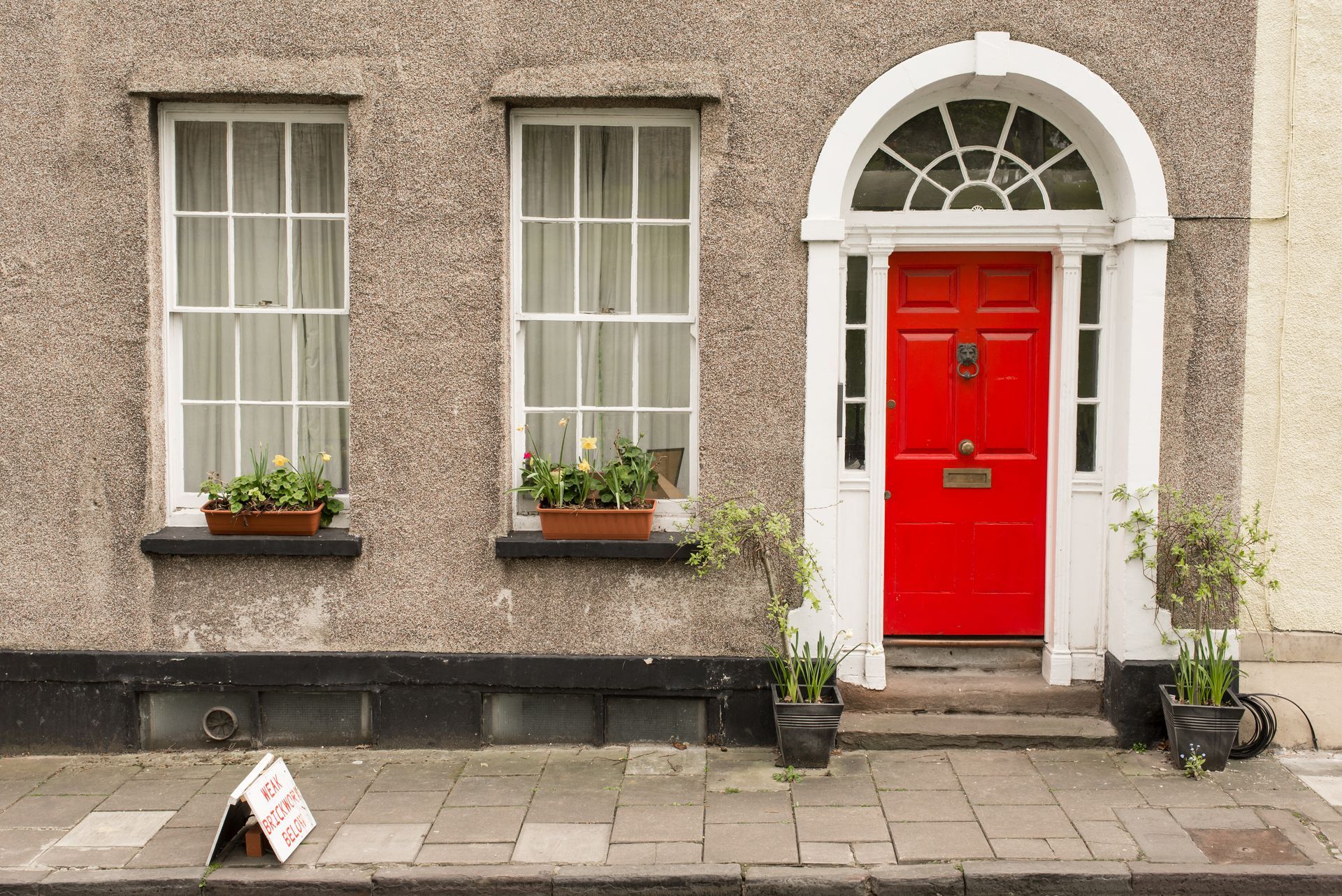 The front of a house with a red door and two windows