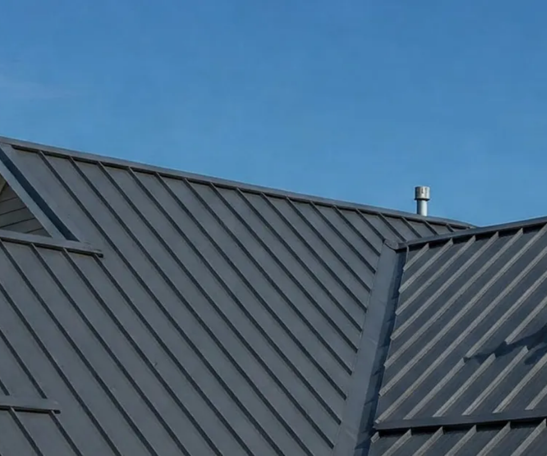 Dark gray metal roof panels under a blue sky