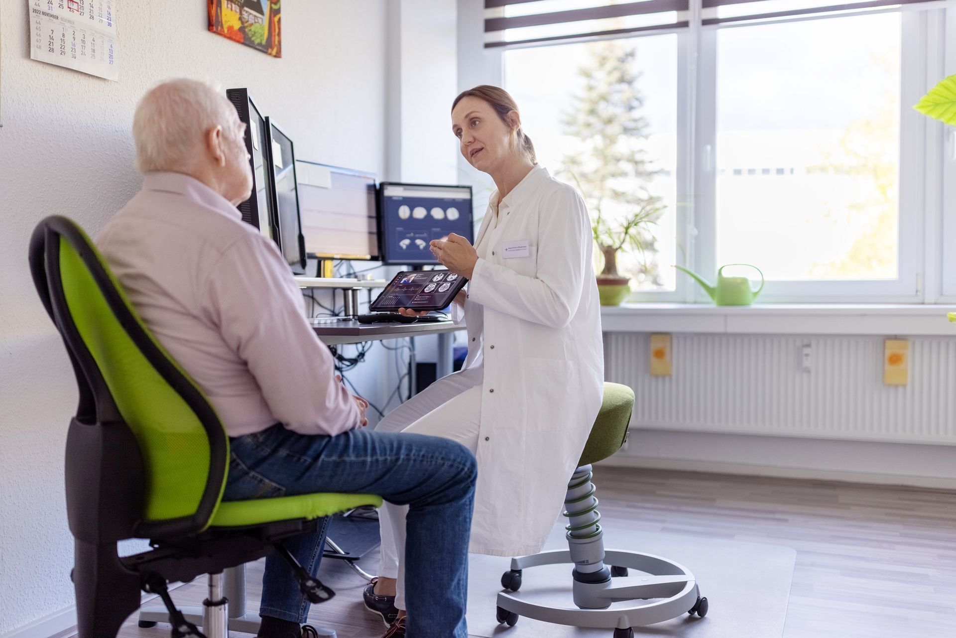 Neurosurgeon reviews brain scans with elderly patient during a consultation in a medical office