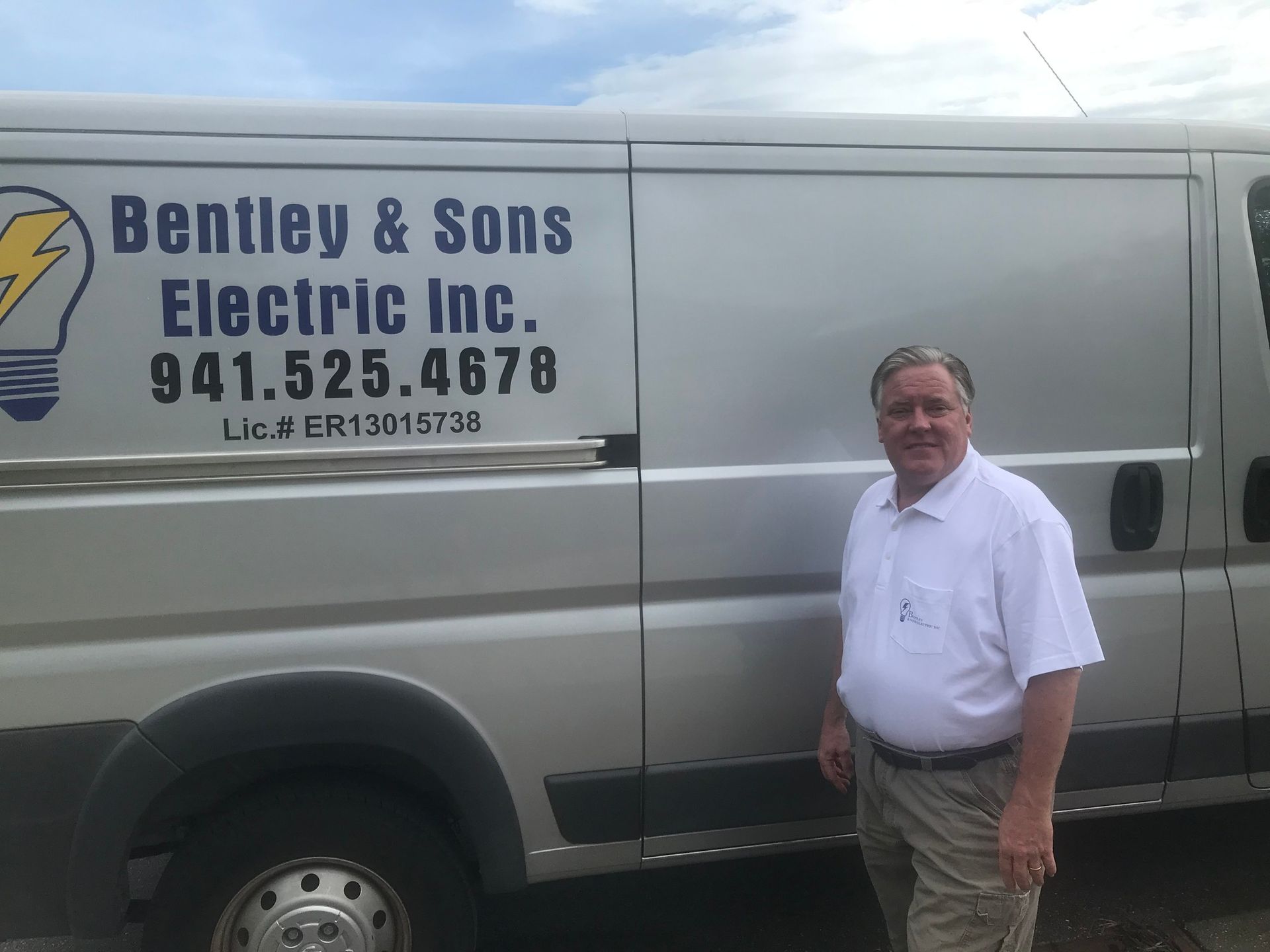 A man is standing in front of a bentley & sons electric inc. van.