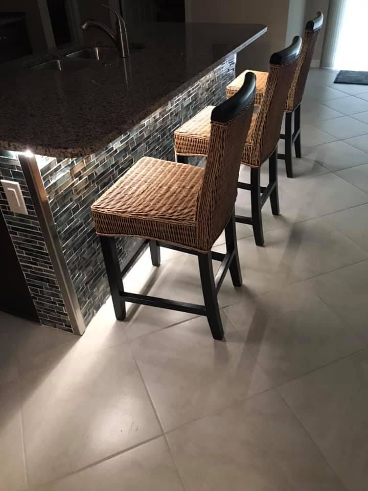 A row of wicker bar stools sitting next to a counter in a kitchen.