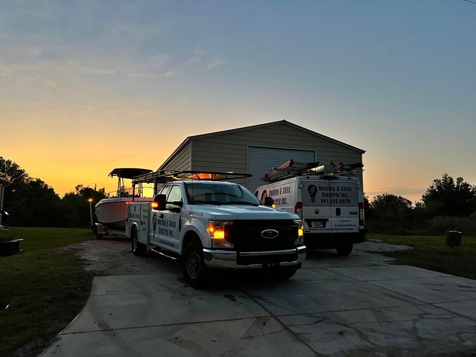 Two trucks are parked in front of a garage at sunset.