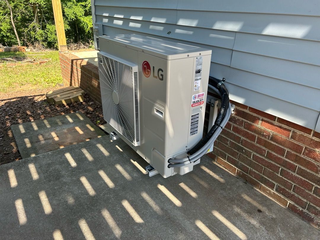 Homeowner clearing grass clippings and debris from an outdoor American Standard condenser coil in As