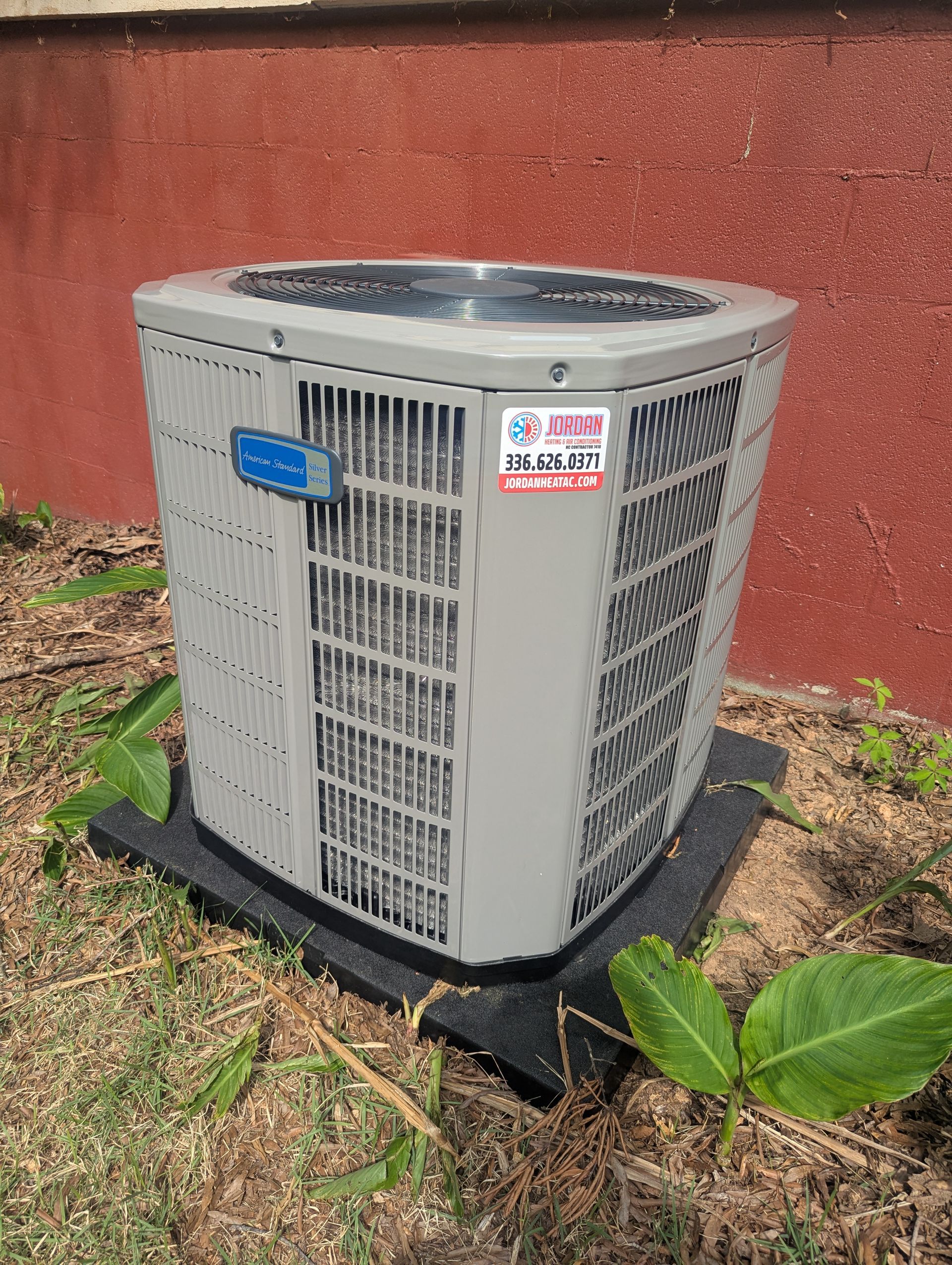 Emergency AC repair technician flushing a clogged condensate drain line in Liberty, NC.