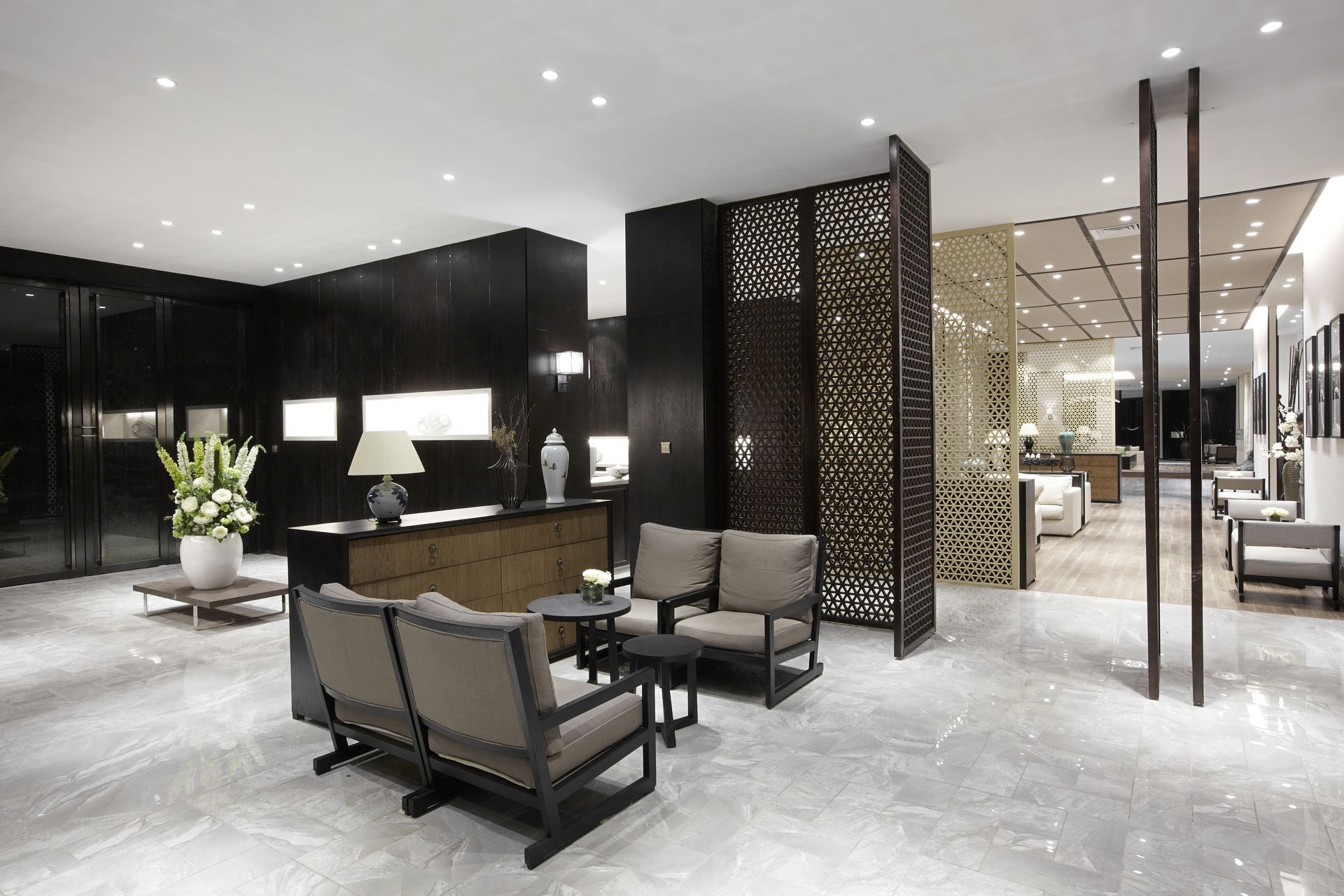 Modern hotel lobby with black decor, lounge chairs, desk, and decorative screens
