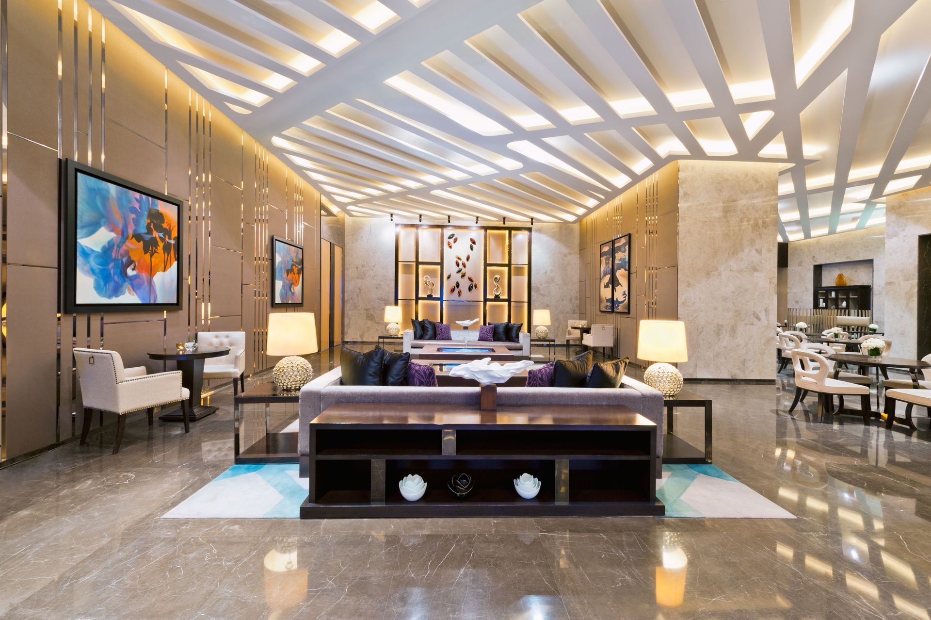 Luxurious hotel lobby with modern seating, glossy floors, and warm geometric ceiling lighting