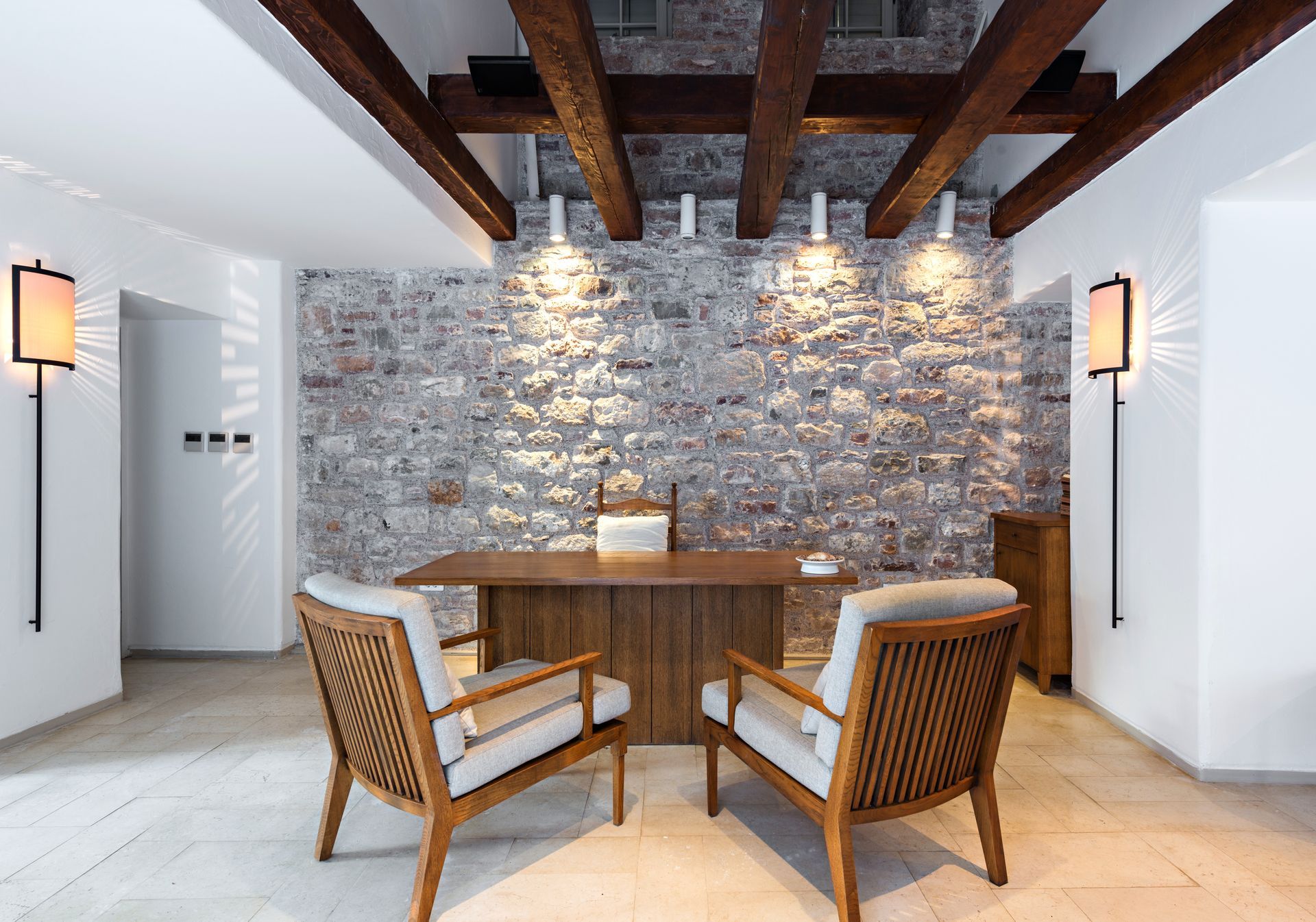 Modern dining nook with stone accent wall, wooden table and chairs, and exposed ceiling beams