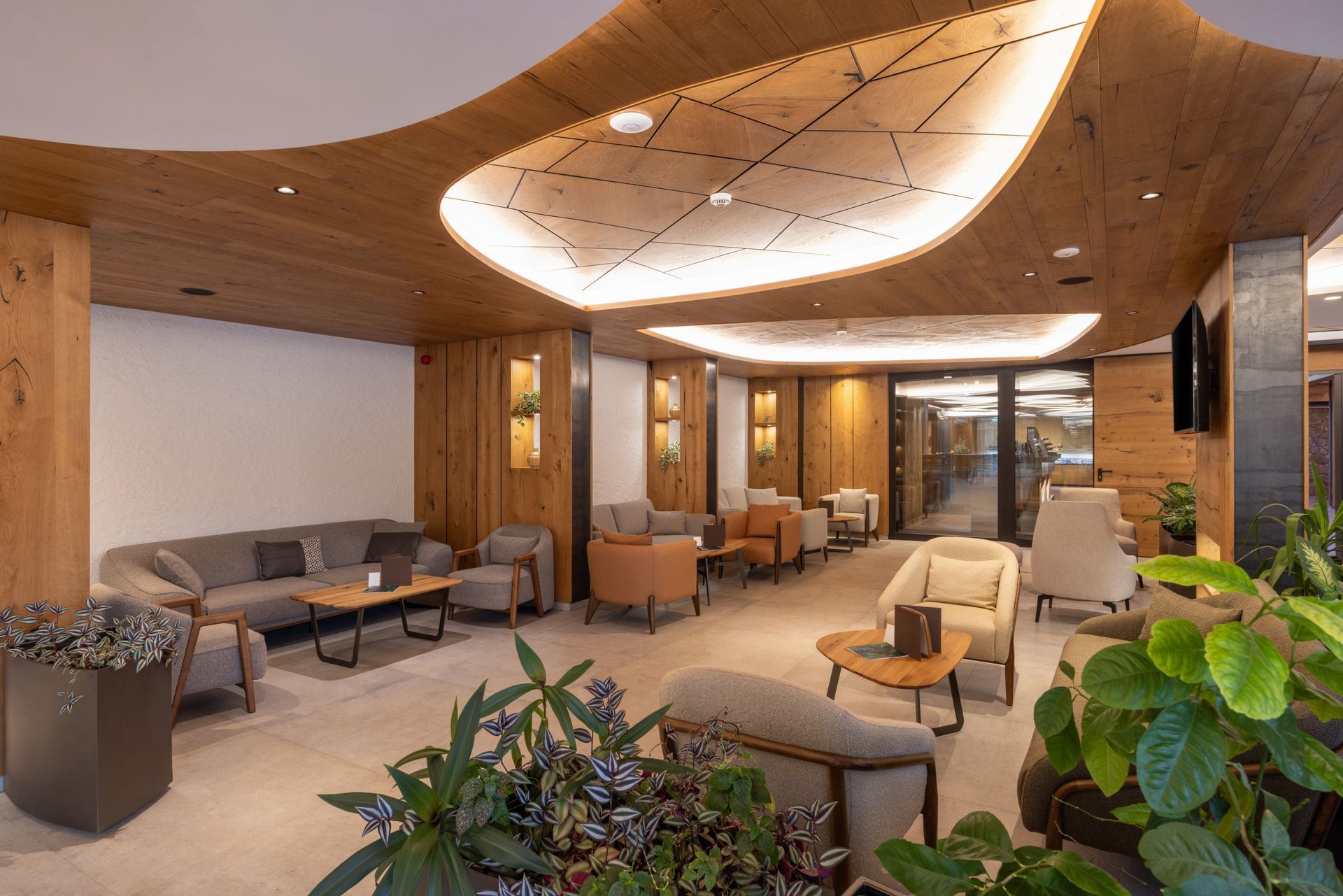 Modern hotel lobby with curved ceiling, warm wood walls, and seating area with sofas and armchairs