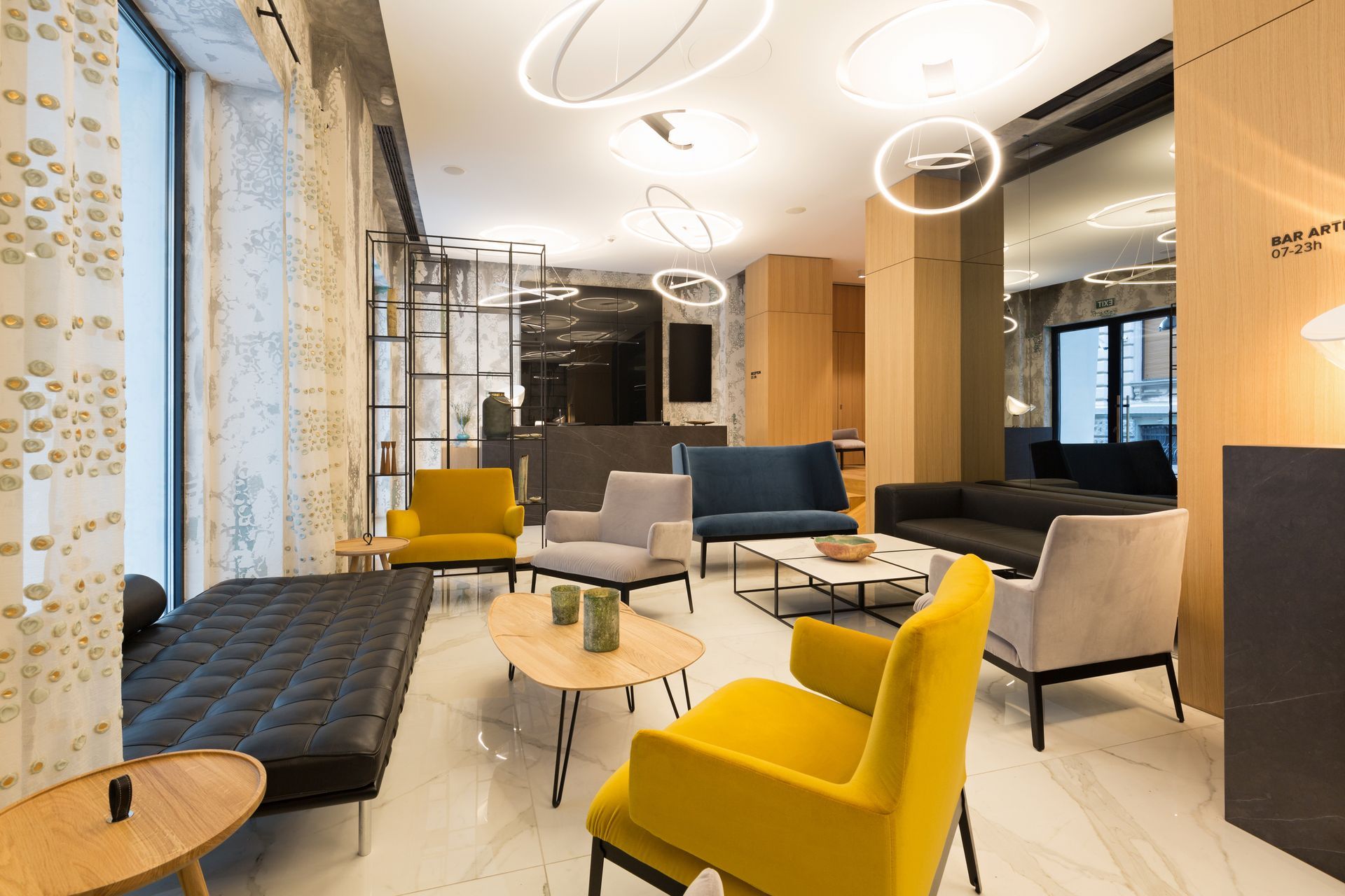 Modern lounge with yellow chairs, gray sofas, glass tables, and circular ceiling lights