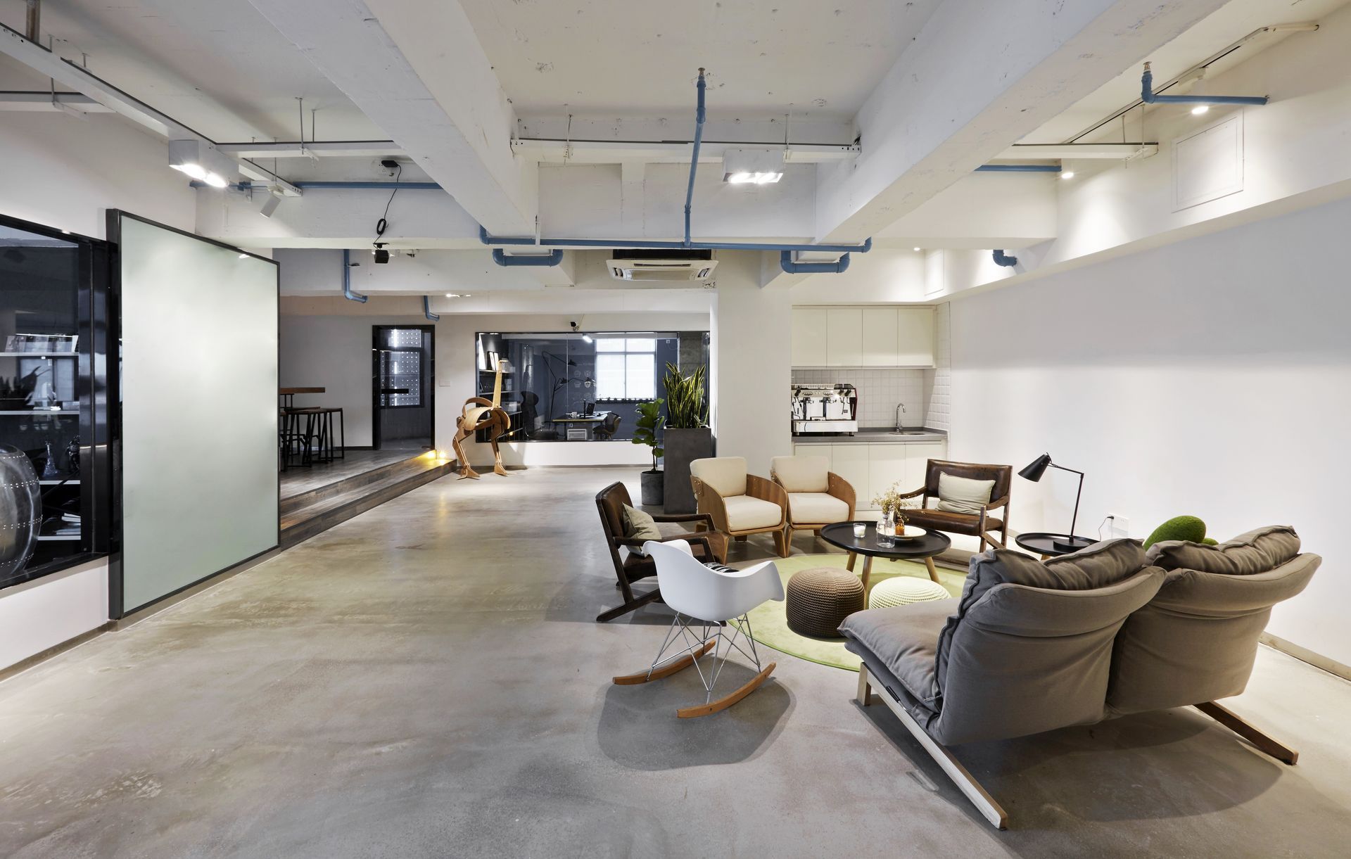 Modern open-plan living room with beige sofas, lounge chair, coffee table, and polished concrete floor