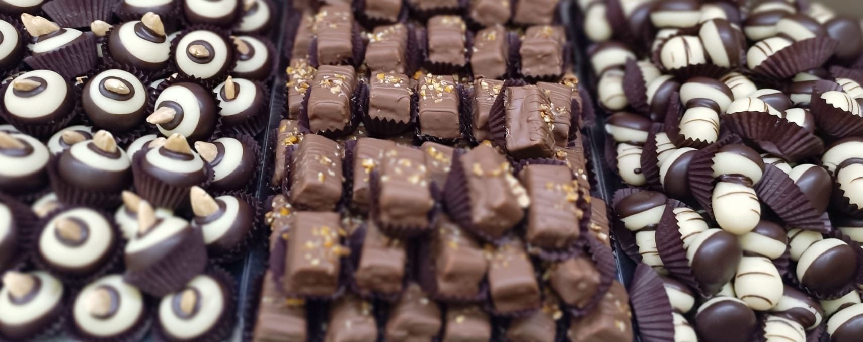 Primo piano di tre varietà di cioccolatini esposti su vassoi.