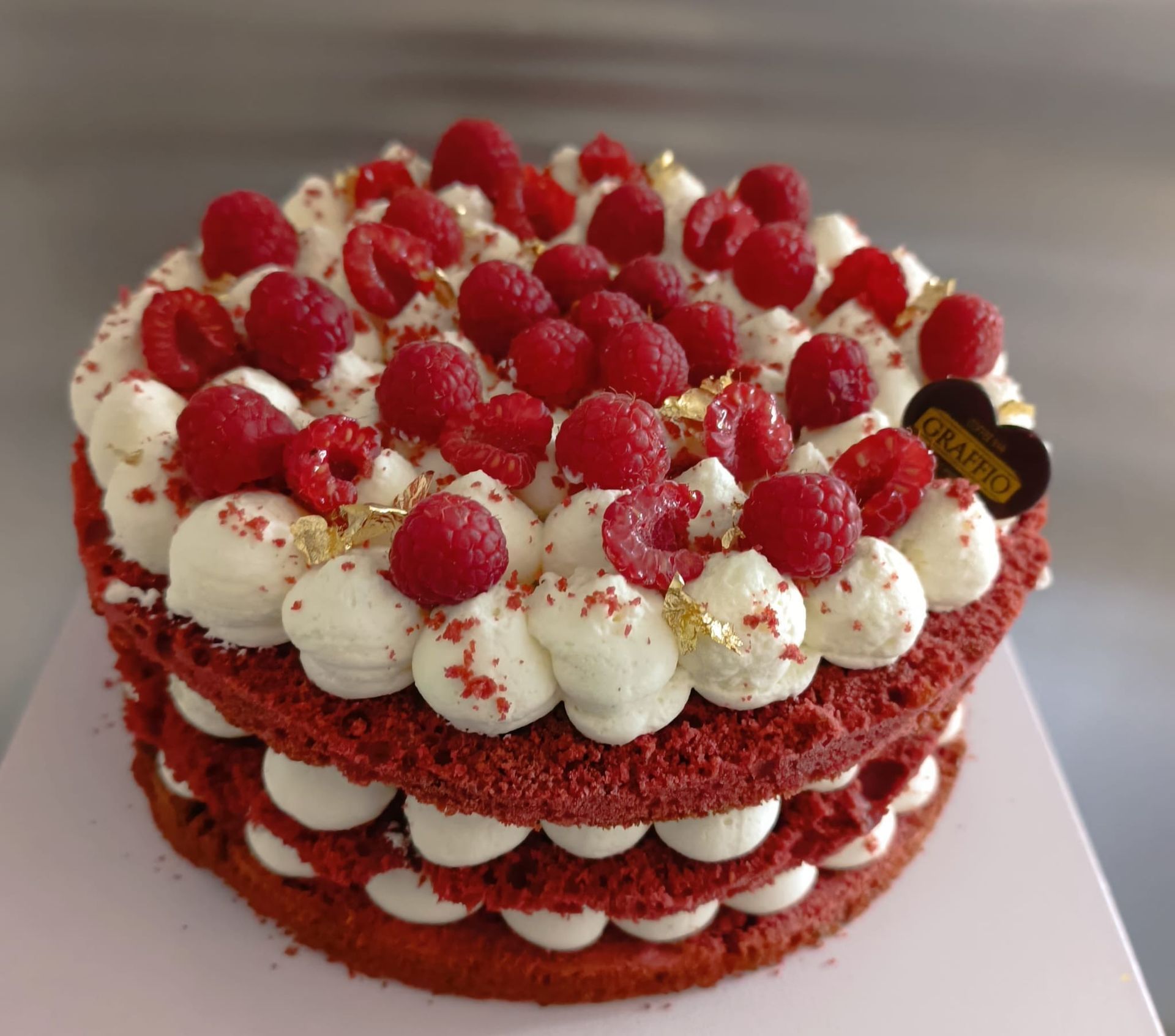 Torta red velvet con glassa bianca e lamponi.