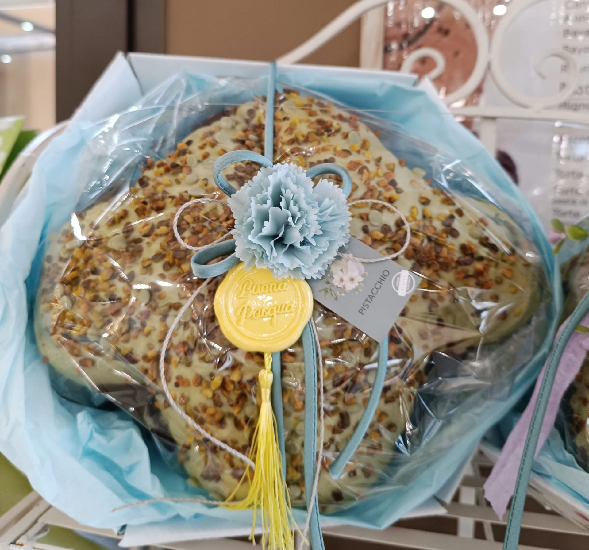 Dolcetto al cioccolato bianco con noci, avvolto in un nastro blu e con una nappa, confezione regalo.