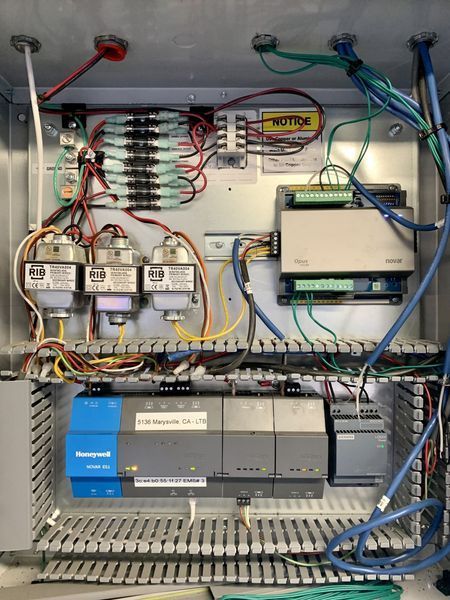 Control panel with wiring, components, and instruments inside a metal enclosure.