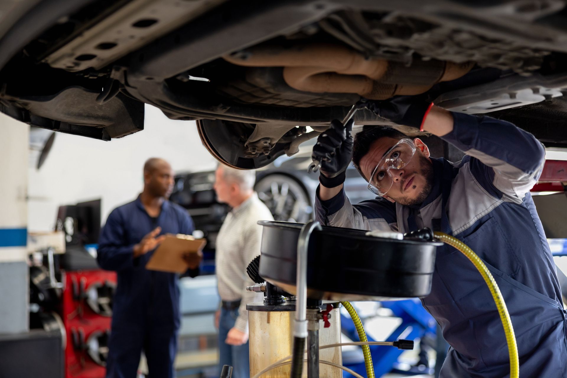 A mechanic working at an auto repair shop fixing a car.