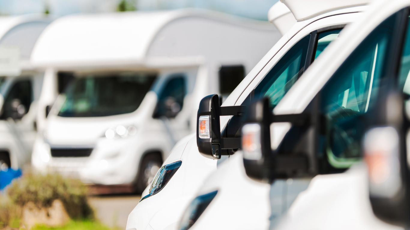 White RVs parked in a row, with side mirrors and windshields visible.