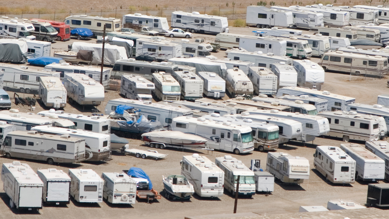 Overhead view of a large lot filled with parked RVs and trailers in various conditions; sunny outdoor setting.