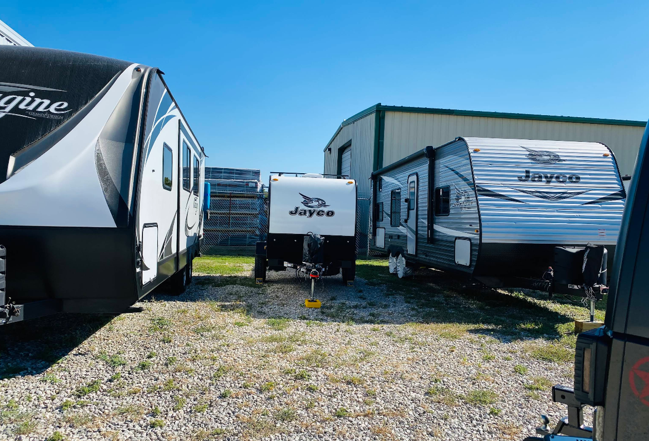Row of white RVs parked, showcasing exterior features like side mirrors and windshields.