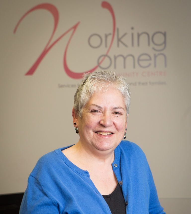 A woman is smiling in front of a sign that says working women