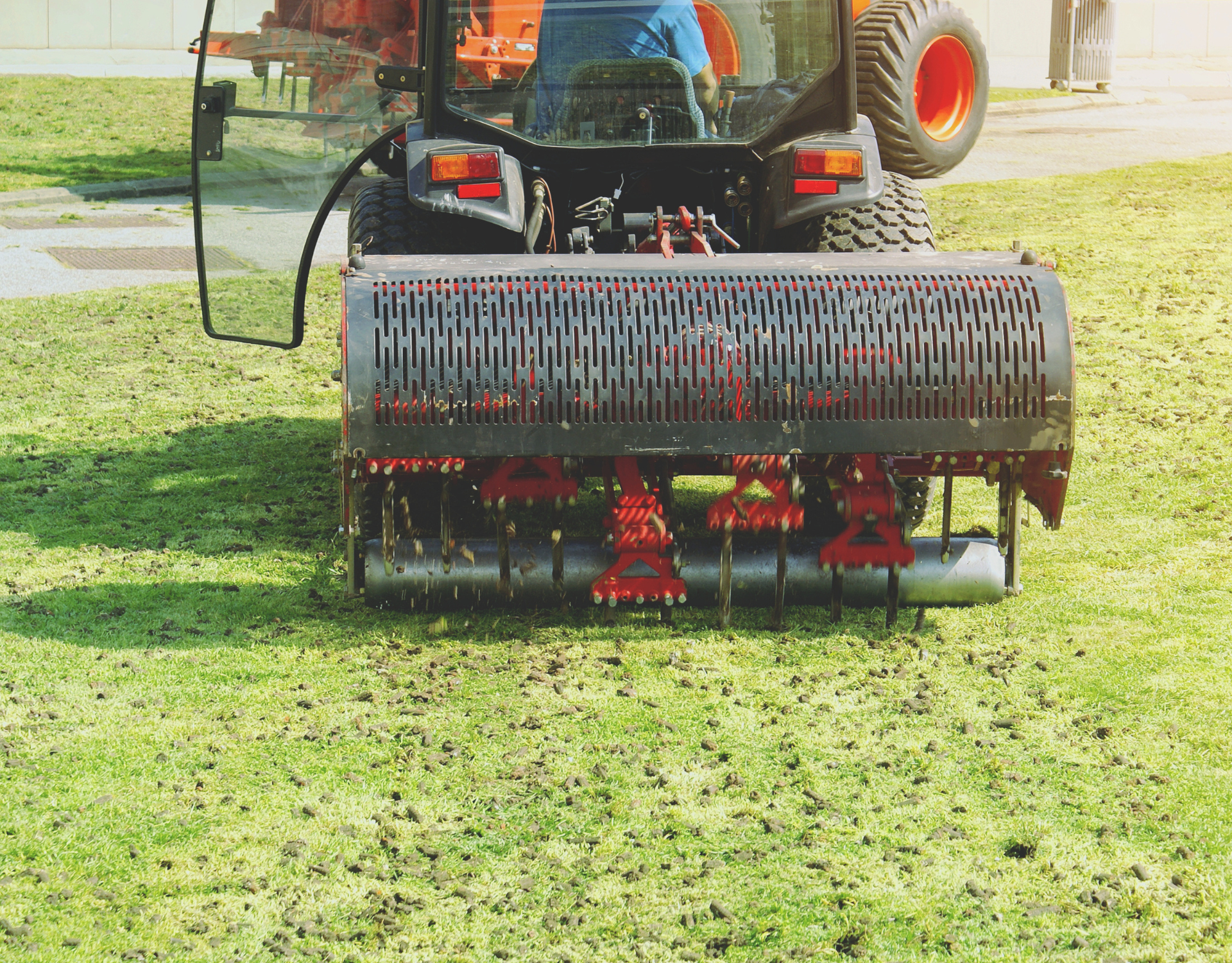A man is driving a tractor on a lush green lawn