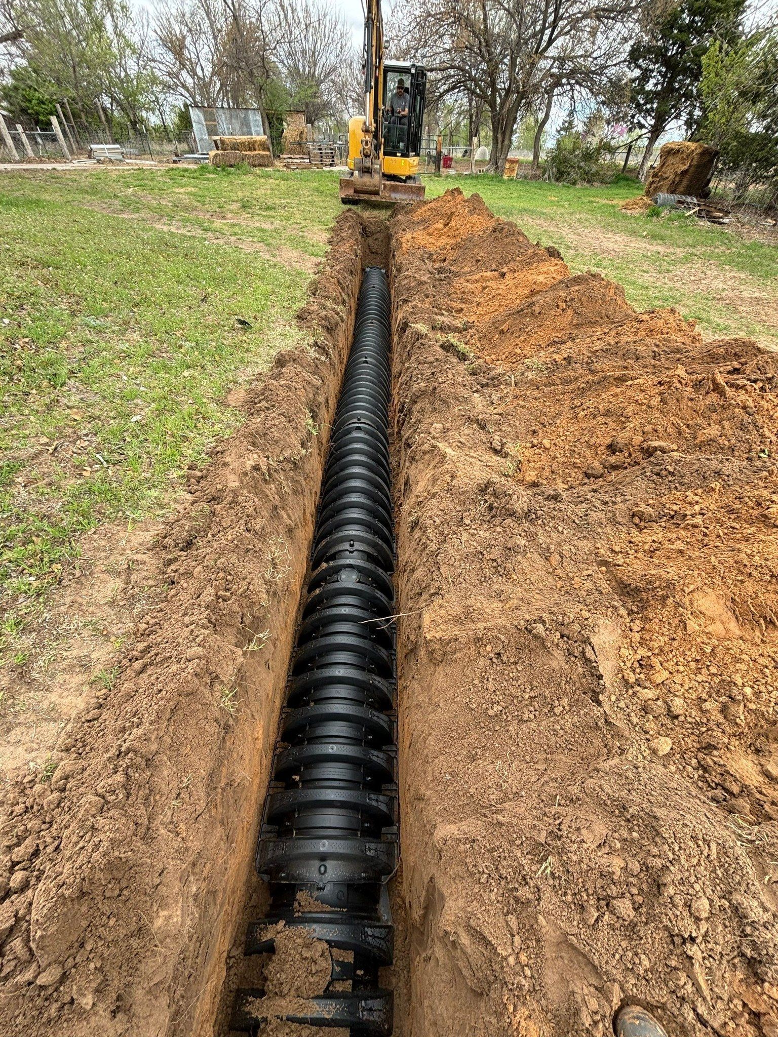 A large pipe is being installed in the dirt in a yard.