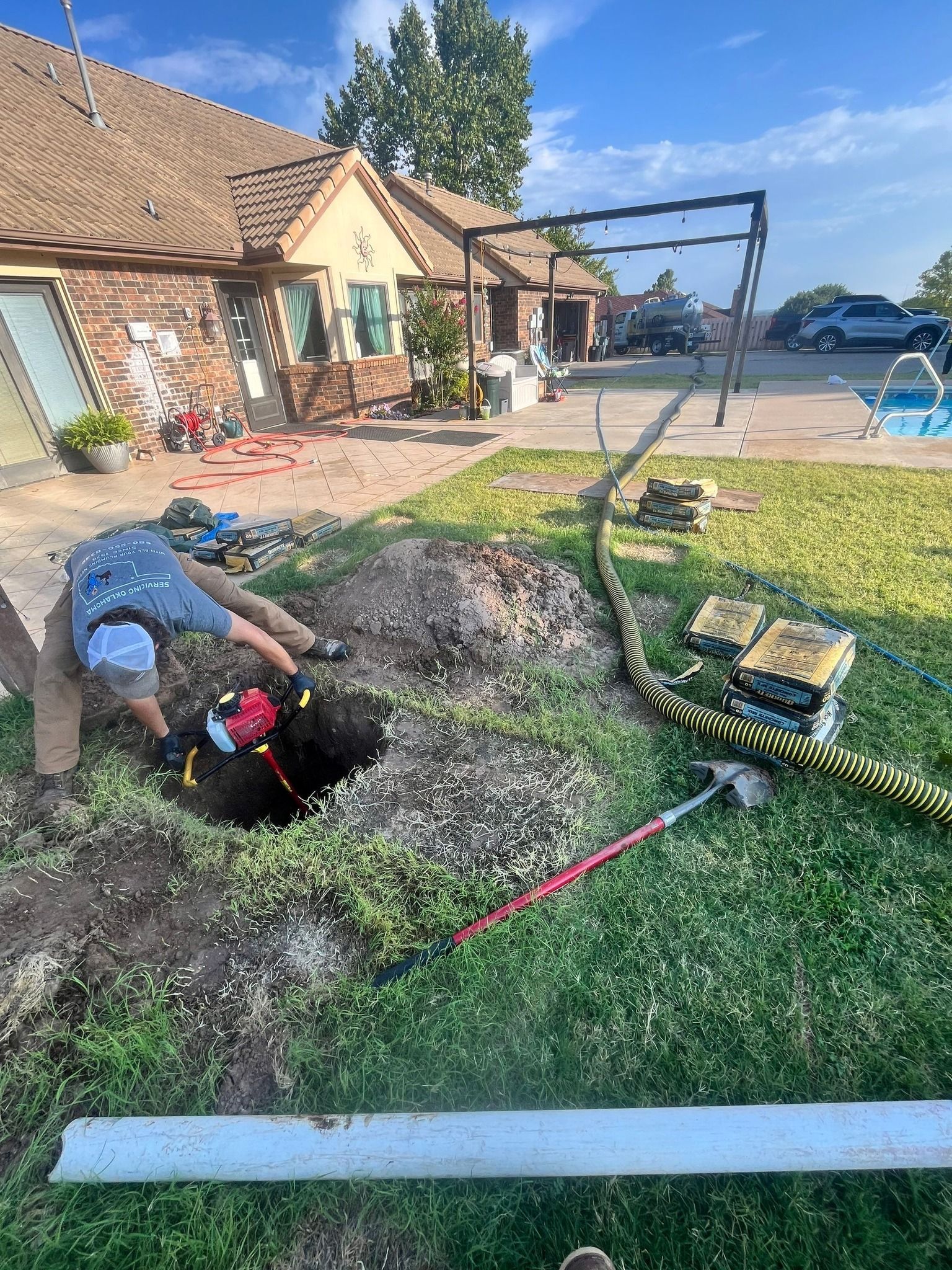 A man is digging a hole in the grass in front of a house.