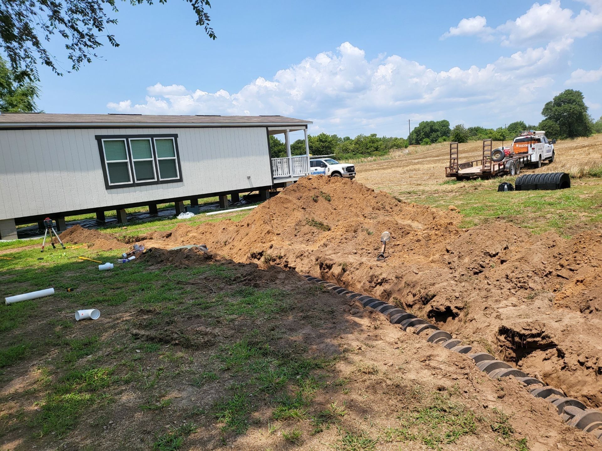 A mobile home is sitting in the middle of a dirt field.