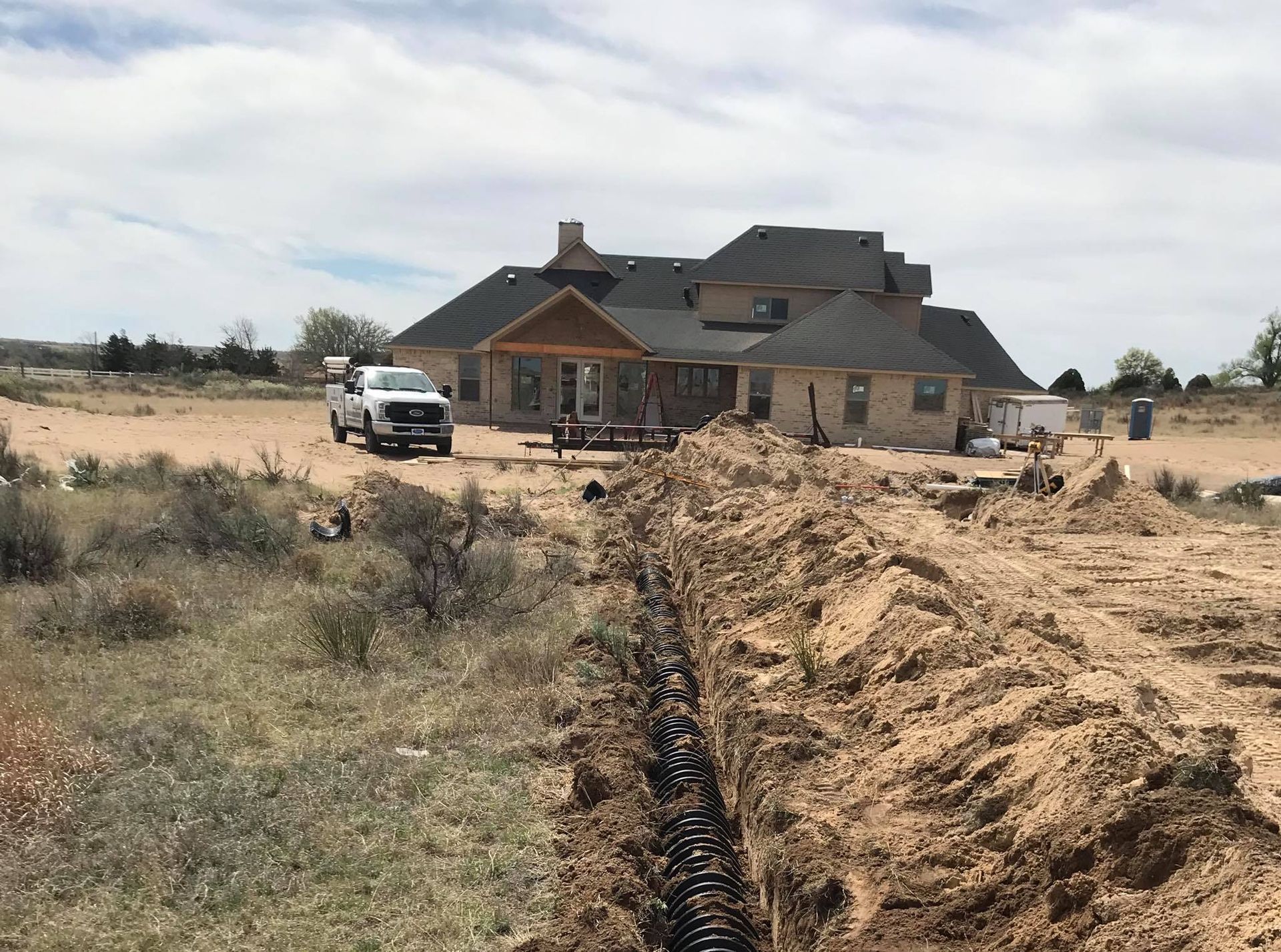 A large house is being built in the middle of a dirt field.