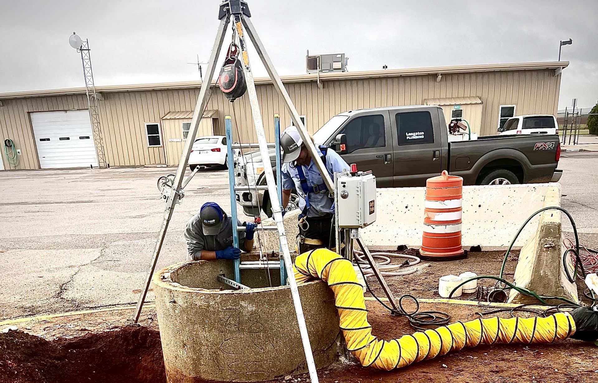 A man is working on a well in a parking lot.