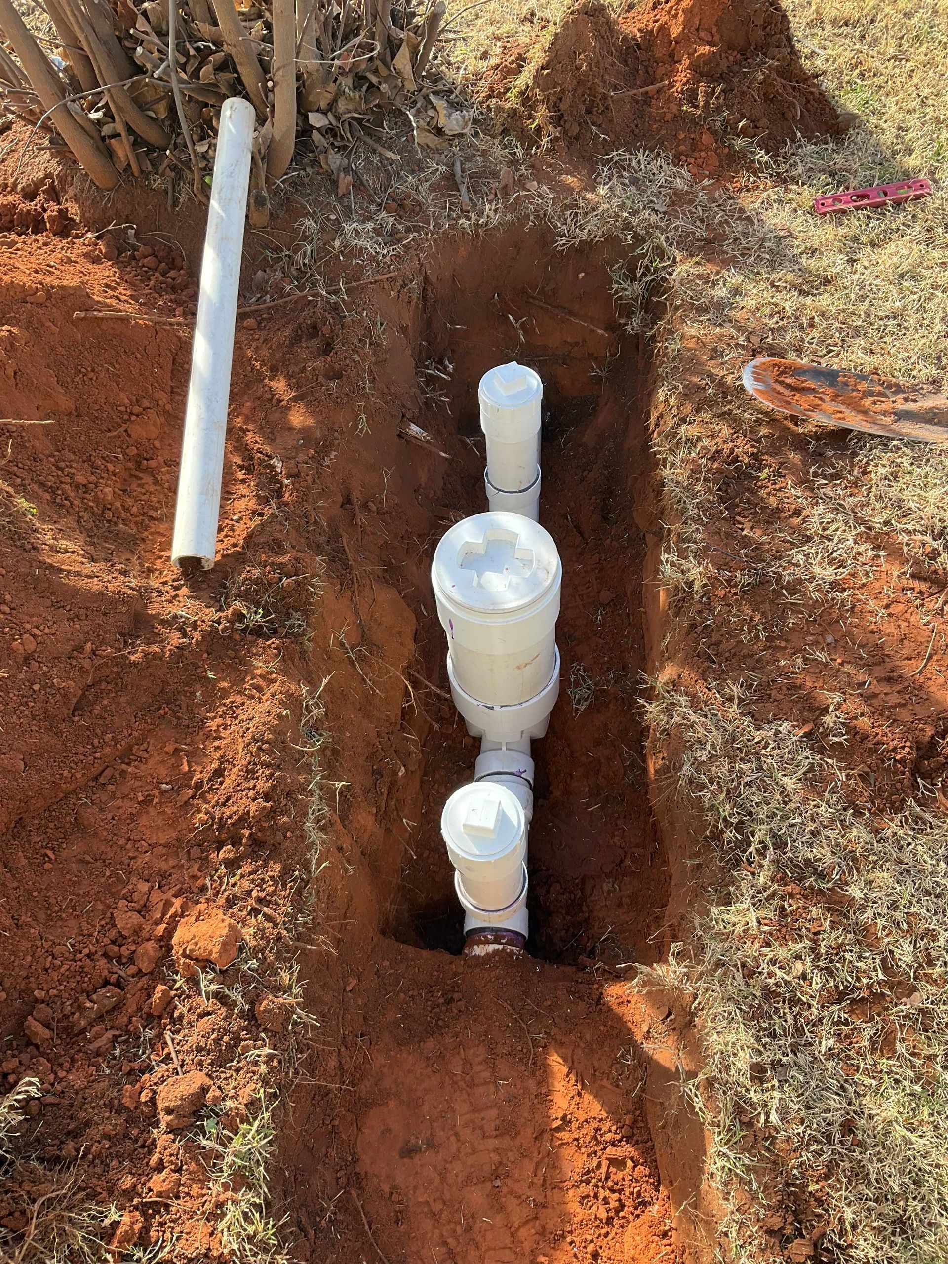 A drain pipe is being installed in a hole in the ground.