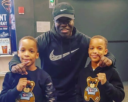 A man is posing for a picture with two young boys wearing teddy bear sweatshirts.