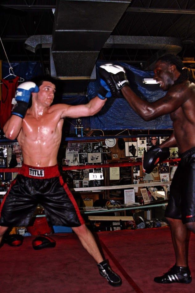 Two men are boxing in a gym and one has the word title on his shorts