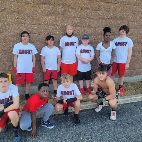 A group of young people are posing for a picture in front of a brick wall.