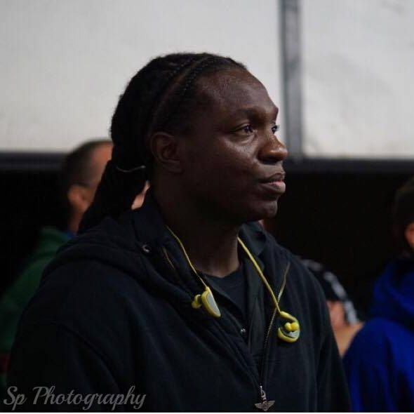 A man wearing ear buds and a black jacket is photographed by sp photography