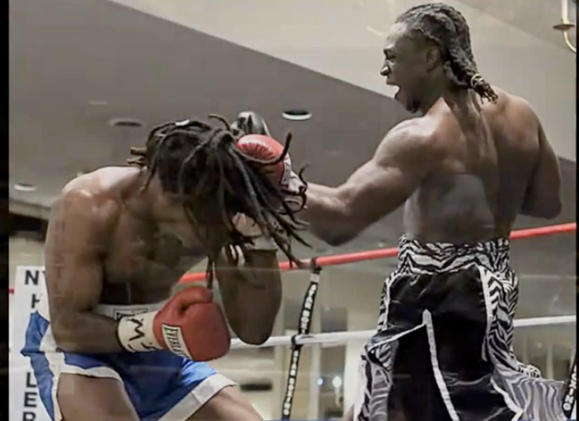 Two men are boxing in front of a sign that says niller