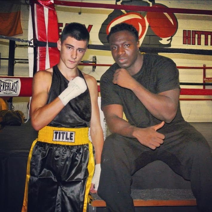 Two boxers posing for a picture with one wearing a belt that says title